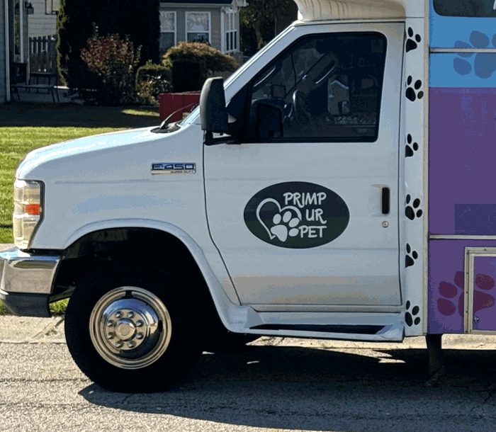 The white cab of the van with the Primp Ur Pet oval on the door and paw prints up the side
